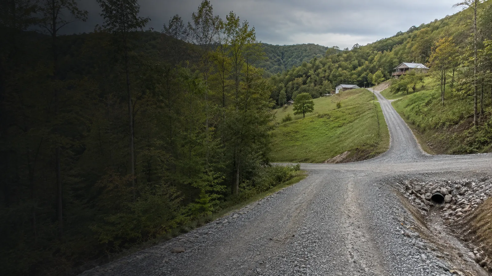 Illustrative view of a gravel access road leading toward hillside homes in Appalachian terrain